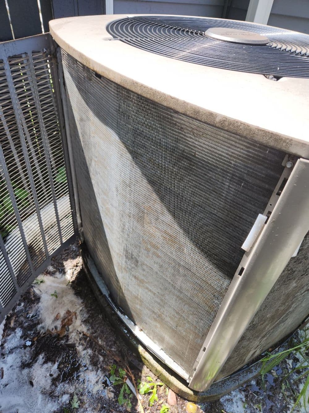 Dirty air conditioning unit with visible grime and debris around the exterior.